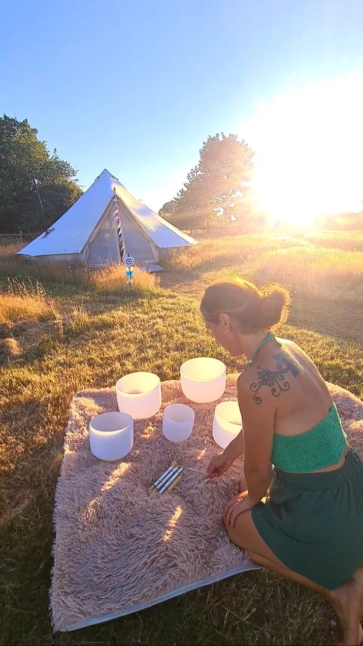 HeartWork practitioner arranging singing bowls beside the bell tent