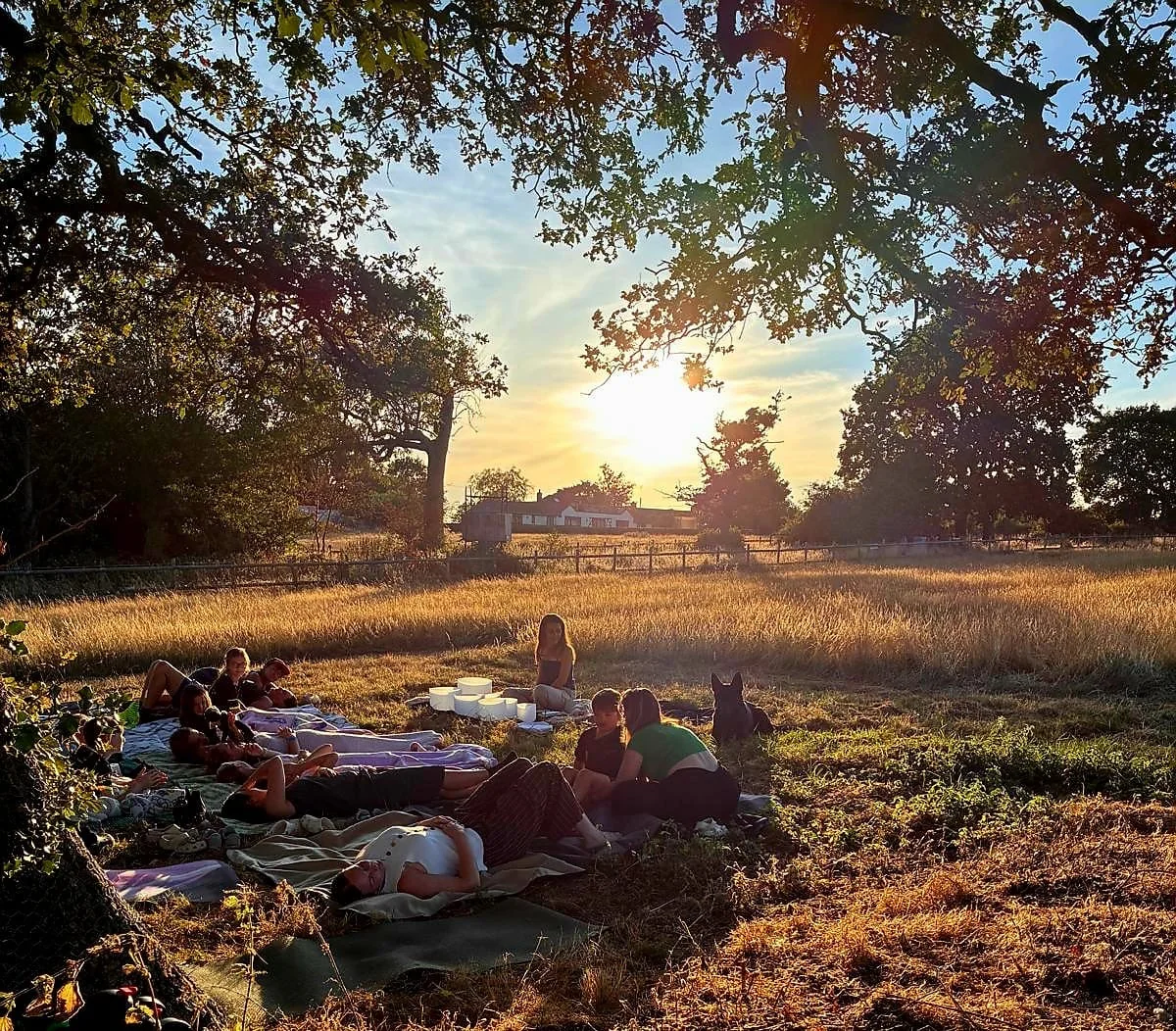 A group resting during an outdoor sound bath at sunset