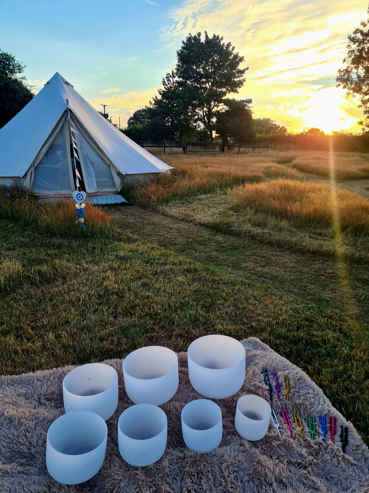 Singing bowls arranged outside the bell tent at sunset